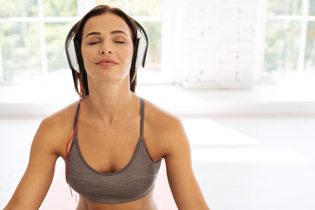 Foto apenas ouça. bela morena usando fones de ouvido e ouvindo música enquanto medita