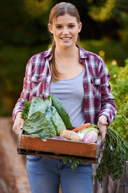 Apenas retrato orgânico de uma jovem feliz segurando uma caixa cheia de legumes recém-colhidos