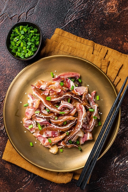 Aperitivo asiático cerdo orejas de cerdo con semillas de sésamo cebolla verde y salsa picante Fondo oscuro Vista superior