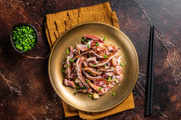 Aperitivo asiático cerdo orejas de cerdo con semillas de sésamo cebolla verde y salsa picante Fondo oscuro Vista superior