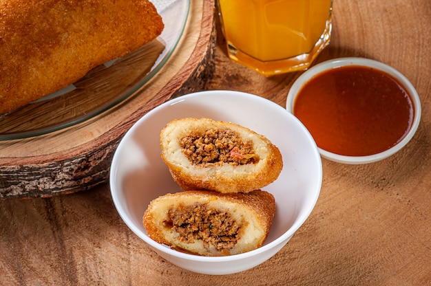 Aperitivo brasileño Croqueta de ternera frita con salsa de pimienta y jugo de naranja