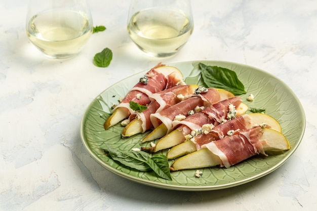 Aperitivo com pêra queijo azul prosciutto presunto e manjericão Antepasto italiano com vinho branco banner menu receita lugar para vista superior do texto