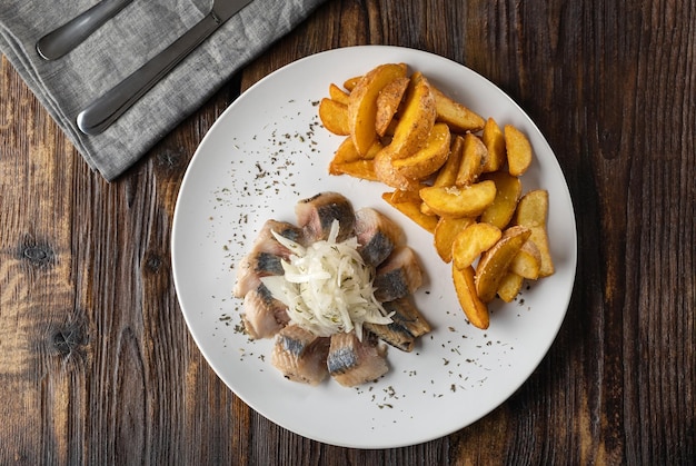 Aperitivo de cerveja de arenque salgado e fatias de batata em um prato