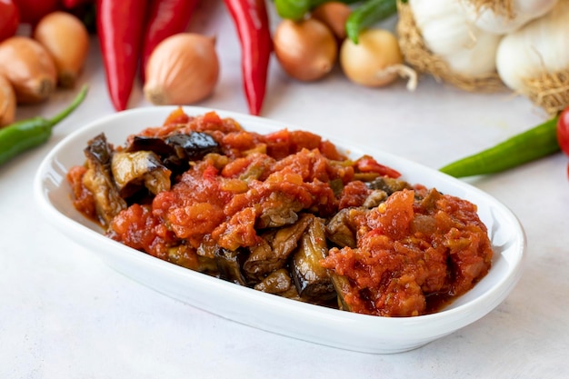 Aperitivo de salada de berinjela grelhada com molho de tomate com molho de berinjela ou saksuka Meze tradicional do Oriente Médio ao lado do prato principal Layout em madeira branca