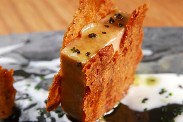 Aperitivo de foie gras con obleas tostadas y aderezos placa de piedra azulejo pizarra comida de mesa de madera