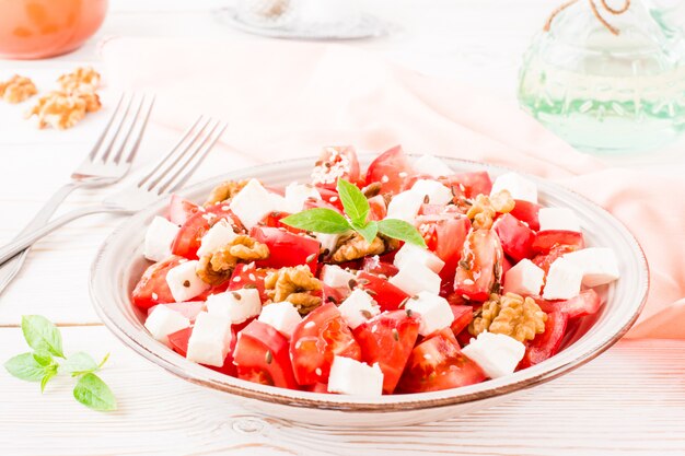 Aperitivo fresco de tomate, queijo feta, nozes, sementes de linho e gergelim em um prato