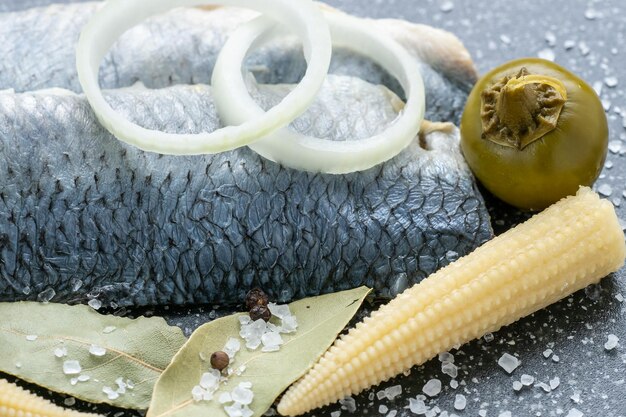 Aperitivo frio de peixe marinado em água salgada Filé de arenque marinado em tábua preta