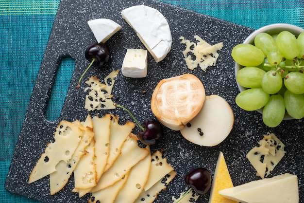 Aperitivo frío Embutidos Queso en tabla de cortar aislado en la vista superior de fondo azul