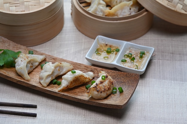 Aperitivo de gyozas fritas y albóndigas con salsa de ciruela en mesa de madera