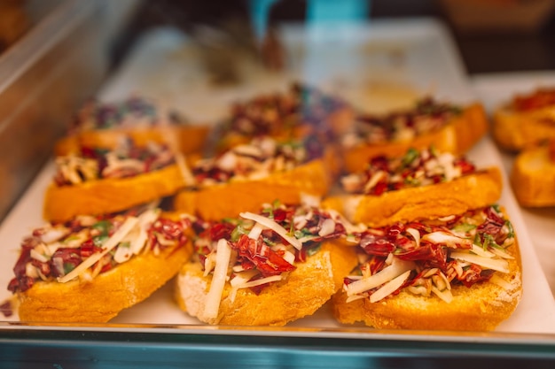 Aperitivo italiano Bruschetta con tomates asados, queso mozzarella, ajo y hierbas a la venta en un marcador de granjero o en un café de la ciudad