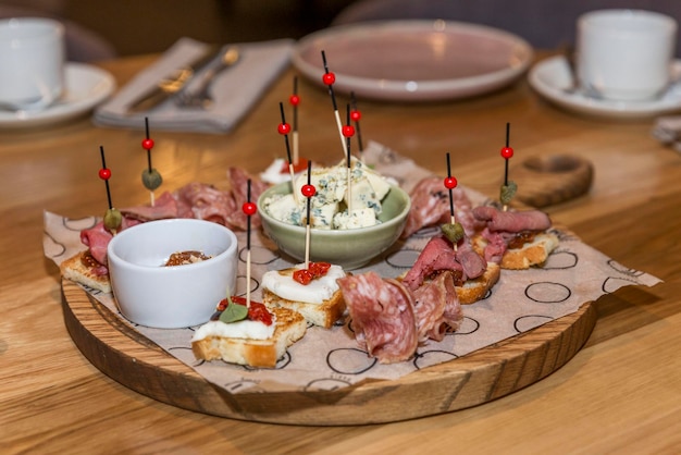 Aperitivo italiano con pan salchicha queso tomates y salsas en una tabla de madera sobre la mesa