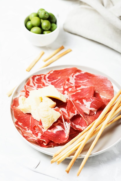 Aperitivo italiano tradicional con palitos de queso, jamón y pan, enfoque selectivo