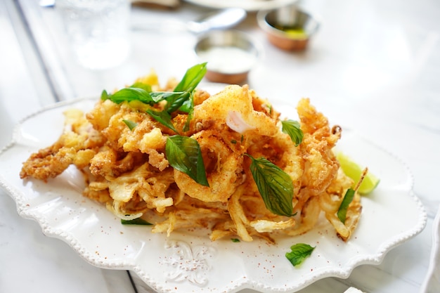 Aperitivo de lujo y calamar crujiente frito en disco blanco, listo para comer.