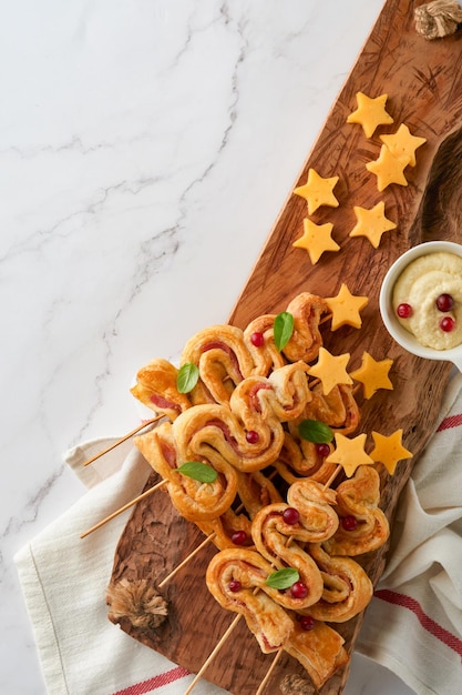 Aperitivo de Navidad o Año Nuevo Bollos de hojaldre con forma de árbol de Navidad con queso y jamón Grupo de formas de árboles de Navidad en tablero de madera Idea festiva para la cena de Navidad o Año Nuevo Vista superior