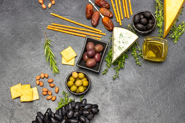 Aperitivo para aperitivo com azeitonas e queijo uvas e tâmaras baguete e bolachas nozes e ramos de tomilho