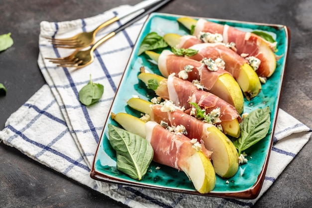 Aperitivo con queso azul de pera y jamón prosciutto sobre un fondo oscuro Grasas saludables Comer limpio para perder peso Vista superior de formato de pancarta larga