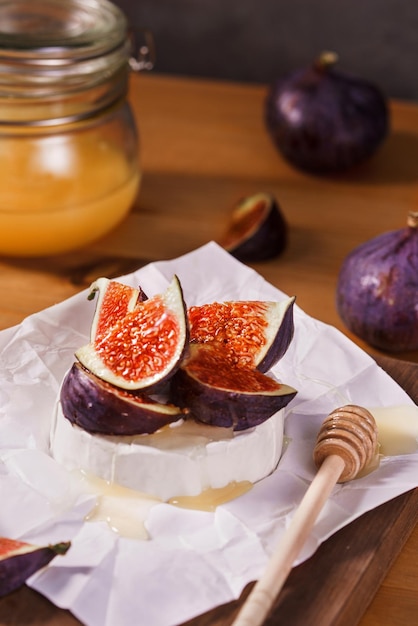 Aperitivo de queso blando cubierto con miel de higos en rodajas sobre fondo de madera