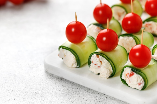 Aperitivo Rolinhos de pepino recheados com cream cheese servidos em um prato branco Canapés de férias