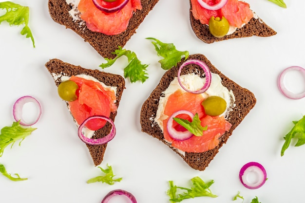 Aperitivo, sanduíche aberto com salmão e cebola no fundo branco. cozinha tradicional italiana ou escandinava. conceito de nutrição adequada e alimentação saudável. layout de configuração plana