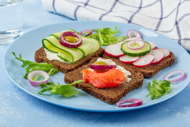 Aperitivo, sándwich abierto con salmón en un plato azul. Cocina tradicional italiana o escandinava. Concepto de nutrición adecuada y alimentación saludable. De cerca