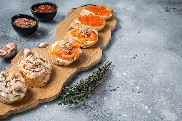 Aperitivo de tostadas de salmón ahumado y caviar rojo con queso crema. Fondo gris. Vista superior. Copie el espacio.