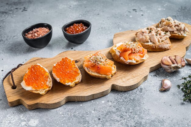 Aperitivo de tostadas de salmón ahumado y caviar rojo con queso crema. Fondo gris. Vista superior.