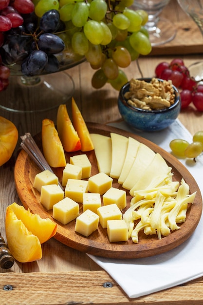 Un aperitivo de varios tipos de quesos, uvas y nueces, servido con vino. Estilo rústico.