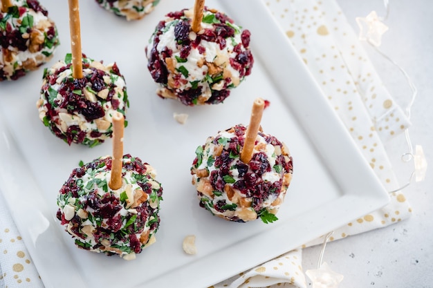 Aperitivos de bola de queijo de Natal com cranberries, nozes e ervas.