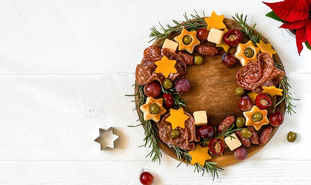 Aperitivos de natal grinalda tábua de corte de madeira e mesa de madeira branca com espaço de cópia de texto