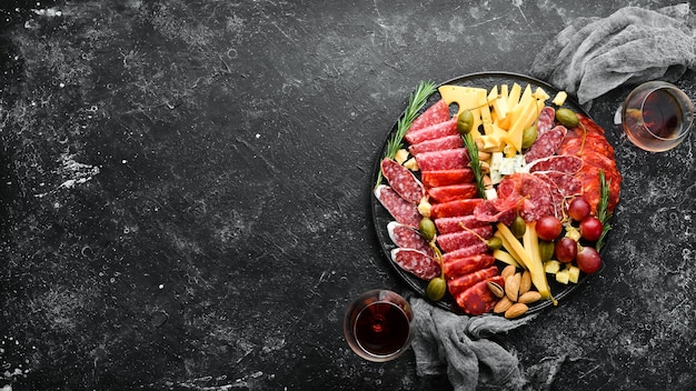 Aperitivos italianos antipasti queso y vino en copas Vista superior Sobre una mesa de piedra negra Espacio libre para el texto