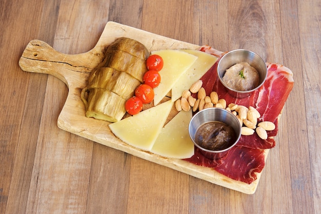 Aperitivos de queso y jamón sobre fondo de madera.