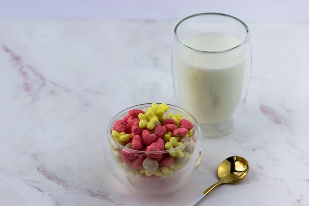 Aperitivos con sabor a frambuesa y plátano en forma de corazones y flores Un bol con un desayuno rápido y un vaso de leche sobre un fondo blanco