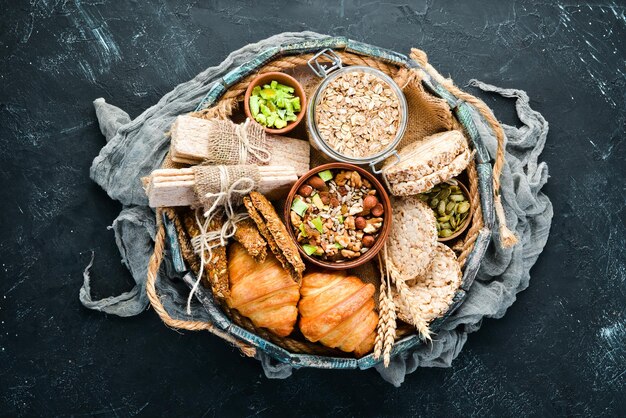 Aperitivos saludables en una caja de madera barras de avena croissant pasas nueces Vista superior Espacio libre para el texto