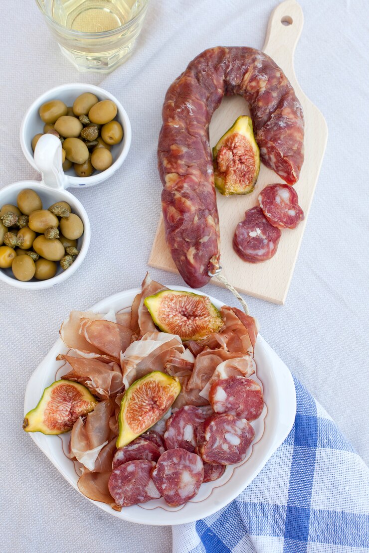 Aperitivos tradicionales de carne mediterránea con aceitunas, higos y vino blanco.