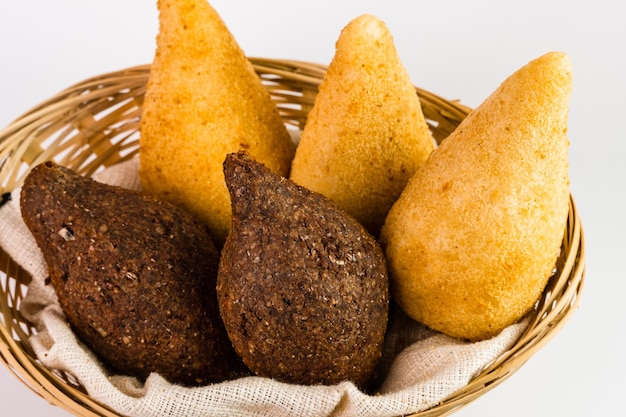 Aperitivos tradicionales Pollo Coxinha conocido como Coxinha en Brasil y Kibe frito servido en una cesta Fondo blanco Enfoque selectivo