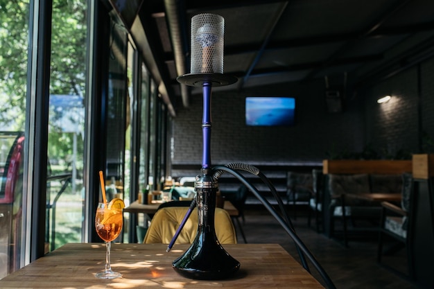 Foto aperol-spritz cocktail aperol-spritz in der nähe der wasserpfeife shisha auf dem hintergrund des restaurants shisha-rauch köstlicher aperol-spritz auf dem tisch