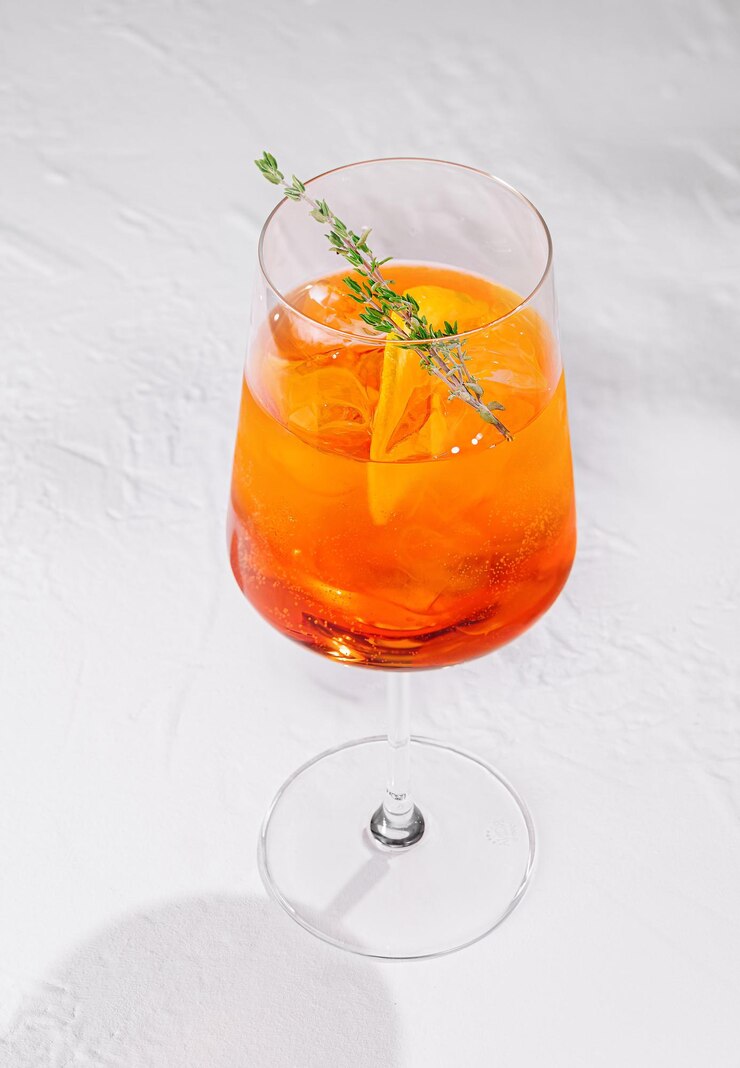 Aperol spritz cóctel de pie en la mesa blanca con guarnición de tomillo