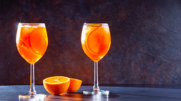 Aperol Spritz cóctel sobre fondo oscuro. Dos vasos de aperol spritz con rodajas de naranja.