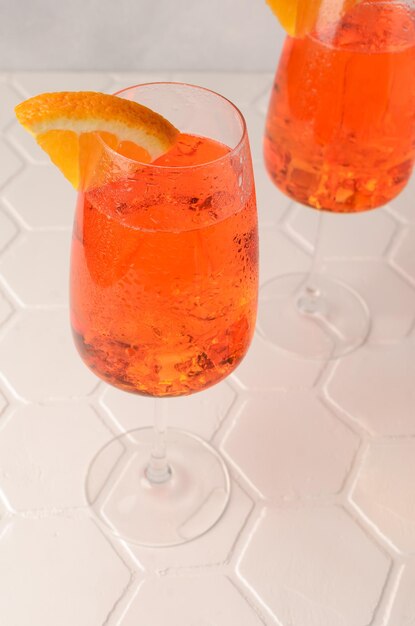 Foto aperol spritz coquetel de verão frio com aperitivo prosecco gelo e fatia de laranja em um copo sobre o fundo branco copiar espaço para texto