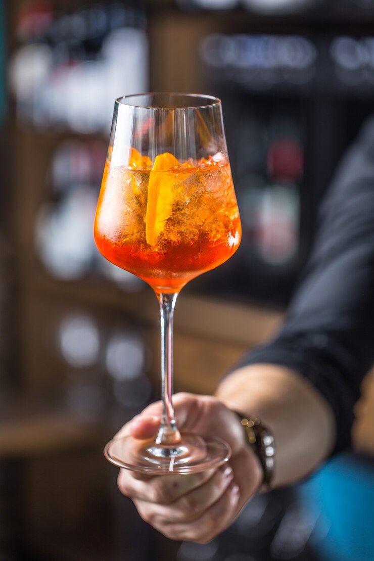 Aperol-Spritz-Getränk. Barkeeper-Hand, die Glas mit Aperol Spritz-Getränk hält.