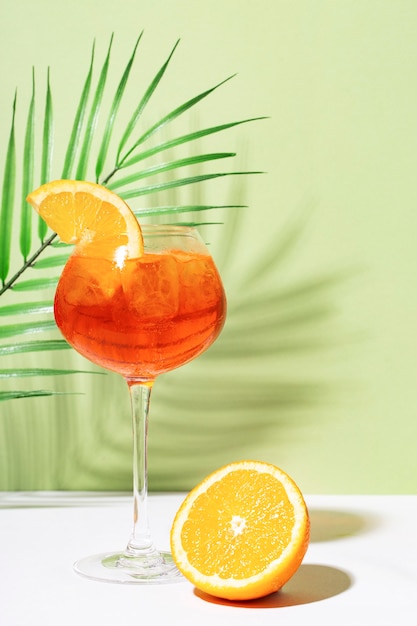 Aperol spritz sobre mesa blanca y pared verde