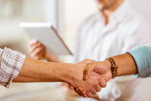 Aperto de mão de dois jovens empresários em roupas casuais.