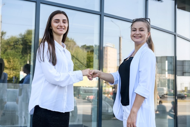 Aperto de mão de mulheres bonitas perto da entrada de um prédio comercial