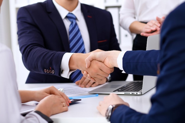 Aperto de mão de negócios na reunião ou negociação no escritório. Os parceiros estão satisfeitos porque assinam contrato ou papéis financeiros.