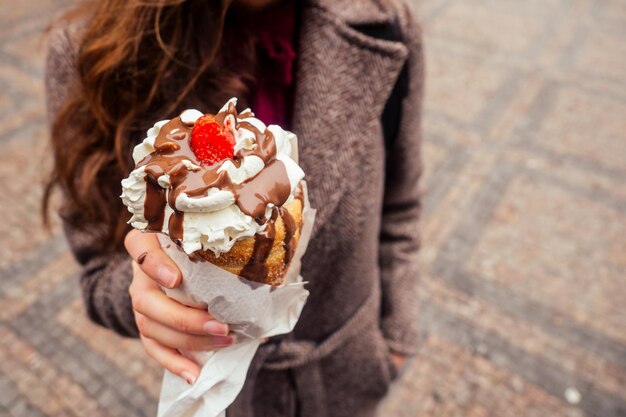 El apetito come un dulce tradicional checo Trdelnik con crema de vainilla y fresas en la calle Praga