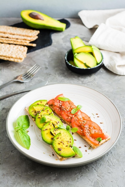 Apetitosa bruschetta con aguacate y tomates en pan de grano en un plato sobre la mesa Comida vegetariana saludable Vista vertical