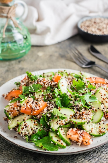 Apetitosa ensalada de pepinos tomates una mezcla de quinoa y perejil en un plato sobre la mesa Comida vegetariana Vista vertical