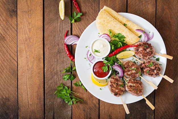 Apetitosa kofta kebab (albóndigas) con tacos de salsa y tortillas en un plato blanco