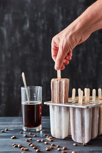 Apetitosa paleta de helado de café en un palito con un vaso de café frío