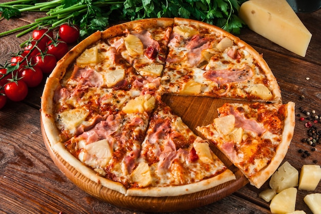 Apetitosa pizza com presunto, queijo e abacaxi, servida em mesa rústica de madeira com ingredientes. Corte uma fatia da mordida.